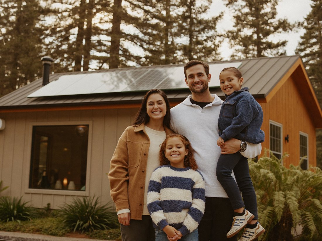 A happy Pacific Northwest family in front of their solar-powered home