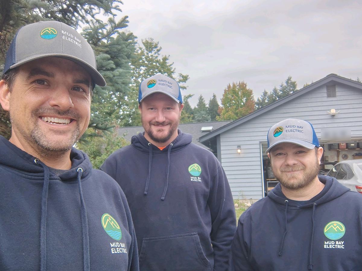 The Mud Bay Electric crew in branded hoodies and caps at a residential solar job site near Olympia, Washington
