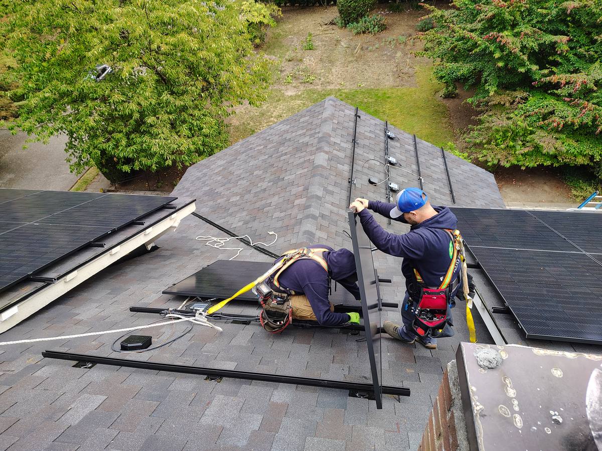 Mud Bay Electric crew harnessed on a roof setting solar rails and microinverters near Olympia, Washington